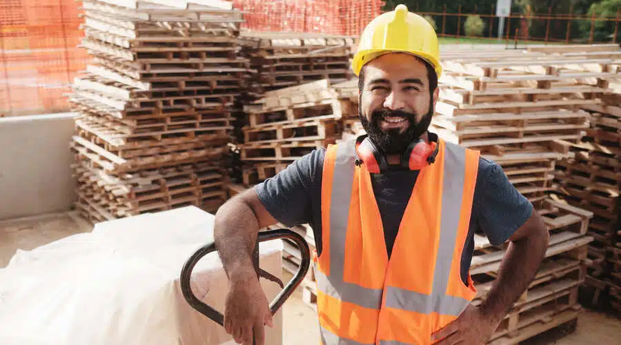 Construction worker stands with machinery used to reduce manual handling.