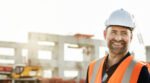 A health and safety representative smiles at the camera on a construction site.