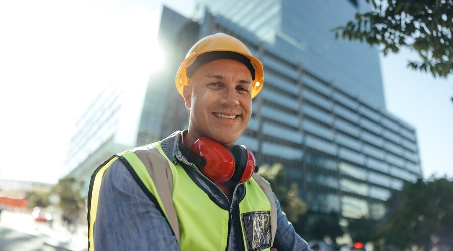 A confident Leading Hand smiles at the camera in front of a completed building.