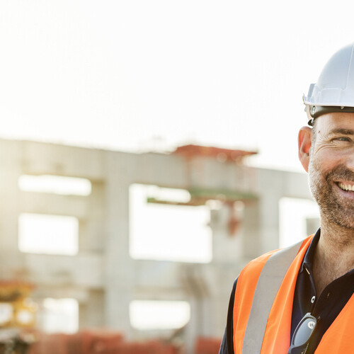 A health and safety representative smiles at the camera on a construction site.