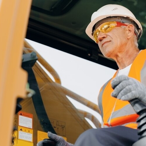 Image of a construction worker operating a forklift. Before starting he consulted a Safe Operating Procedure.